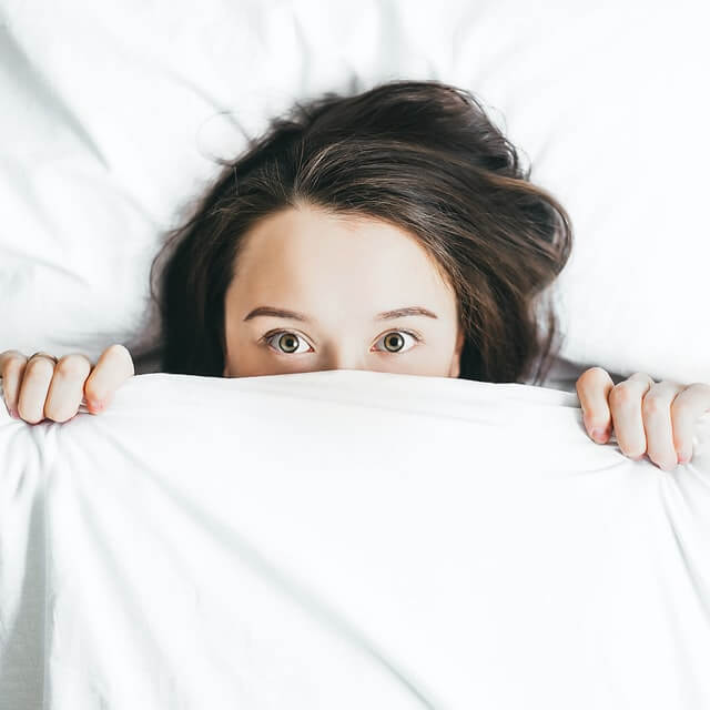 A woman with social anxiety hides under the covers