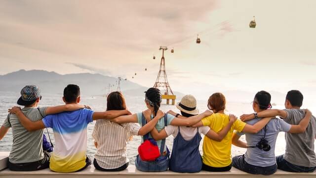 A group of good friends sit in a row and can help you build happiness habits that improve well being